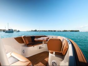 A stylish interior view of a boat's seating area, showcasing comfortable leather seats and a scenic backdrop of the water, perfect for relaxing while cruising.