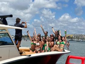 A lively group of friends celebrates on the bow of a boat, capturing fun moments with drinks in hand — perfect for summer parties and memorable outings on the water.