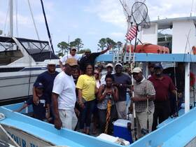 A lively group poses on a fishing boat, ready for a day of adventure on the water — perfect for family outings and fishing trips.
