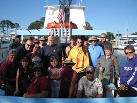A cheerful group of friends and family gather on a fishing boat, ready for a day of adventure on the water. Perfect for creating lasting memories during a fishing trip.