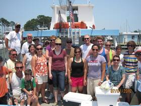 A cheerful group of friends and family gathers on a fishing boat, ready for a day of adventure on the water. Perfect for family outings and fishing trips.