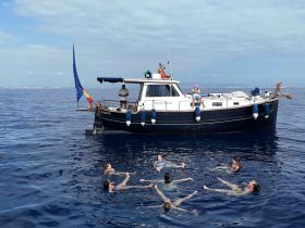 A lively group enjoys swimming in the ocean near their boat, creating a perfect day of fun and relaxation on the water.