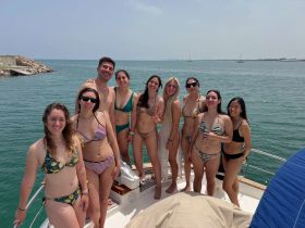 A lively group of friends poses on the deck of a boat, enjoying a sunny day on the water — perfect for summer celebrations and memorable outings.