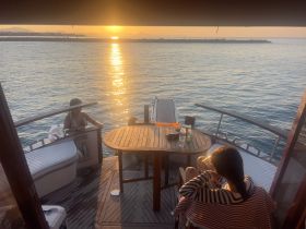 Two guests enjoy a serene sunset view from the deck of a boat, creating a perfect atmosphere for relaxation and memorable moments on the water.