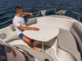 A man relaxes in the comfortable seating area of a boat, showcasing the stylish interior design perfect for leisurely outings on the water.
