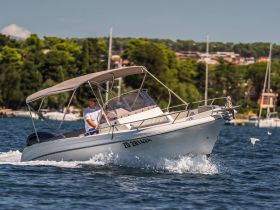 A man navigates a speedboat through clear waters, showcasing the thrill of boating adventures on a sunny day.