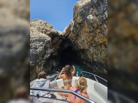 A group of friends captures the moment as they approach a stunning cave on their boat, showcasing the thrill of exploration and adventure on the water.