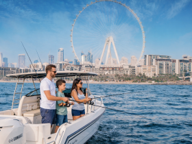 A family enjoys a fishing trip on a boat in Dubai, with the iconic Ferris wheel and city skyline in the background — a perfect blend of adventure and urban scenery.