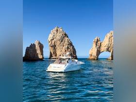 A stunning yacht named 'Breakin' Rules' navigates the clear waters near iconic rock formations, showcasing the beauty of the coastline.