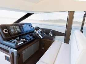 A sleek interior view of a boat's helm and console, showcasing modern navigation equipment and comfortable seating — perfect for luxury cruising.