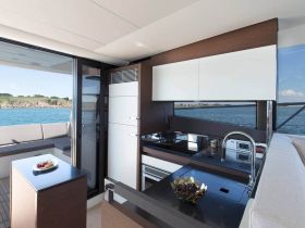 A modern boat interior showcasing a sleek kitchen area with a beautiful view of the water, perfect for entertaining guests while cruising.