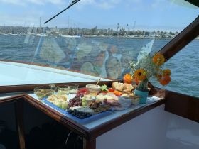 A beautifully arranged charcuterie spread featuring a variety of snacks and fresh flowers, perfect for enjoying on a boat trip.