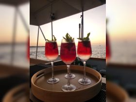 A beautifully arranged tray of cocktails at sunset, perfect for enjoying a relaxing evening on the water. Ideal for boat parties or sunset cruises.