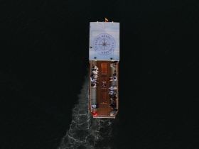 Aerial view of a boat with guests enjoying their time on the water, showcasing a lively atmosphere and the beauty of the surrounding scenery.