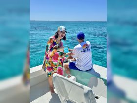 A joyful moment on the water as a woman shares a laugh while fishing with a companion, showcasing the fun and excitement of a day out on the ocean.