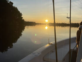 A serene sunset view from a boat, with reflections on the water, creating a picturesque backdrop for a peaceful evening on the water.