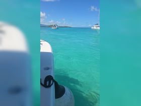 A serene view of a boat navigating through crystal-clear turquoise waters, showcasing the beauty of a tropical destination.