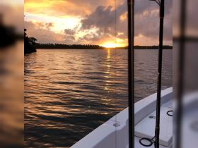 A serene sunset view from the deck of a boat, showcasing the tranquil waters and vibrant sky — perfect for peaceful evening cruises.