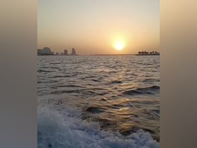 A stunning sunset over the coastline, capturing the serene beauty of the water and skyline — perfect for romantic evening cruises.