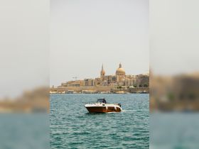 A boat navigates through the waters with a stunning cityscape in the background, showcasing the beauty of coastal exploration.