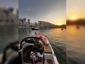 A man relaxes on the deck of a boat at sunset, enjoying the beautiful waterfront view — a perfect moment for celebration and relaxation on the water.
