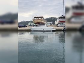 A sleek motorboat docked at the marina, showcasing its modern design against a backdrop of other vessels and a serene water surface.