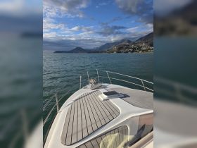 A stunning view from the front of a boat, showcasing the sleek deck and the beautiful mountainous coastline in the background — perfect for exploring serene waters.
