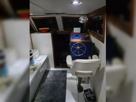 The interior helm of a boat featuring a steering console and seating area, ideal for navigation and comfort while at sea.