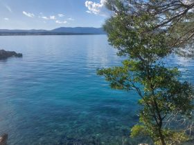 A serene view of calm turquoise waters and distant mountains, perfect for showcasing the beauty of nature.