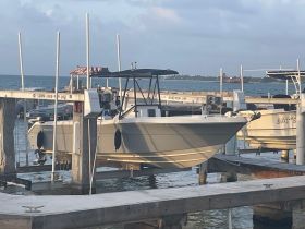A center console boat docked at a marina, showcasing its sleek design against a serene waterfront backdrop.