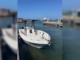 A center console boat docked at a marina, showcasing its sleek design against a clear blue sky — perfect for fishing or day trips.
