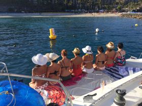 A group of friends enjoys a relaxing day on a pontoon boat, taking in the beautiful beach views while lounging in the sun — perfect for a fun day out on the water.