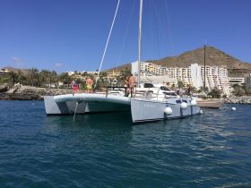 A lively group enjoys a day on a catamaran, with stunning beach views and clear waters, perfect for a fun-filled adventure.