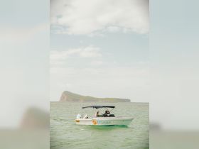 A small boat navigates the waters near a scenic island, showcasing a perfect day for exploration and adventure on the water.