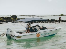 A small boat with passengers navigates through shallow waters, showcasing a perfect day for an excursion. Ideal for exploring coastal areas and enjoying water activities.
