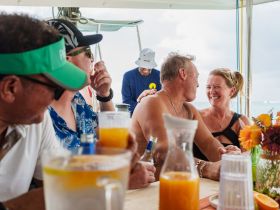 A joyful group of friends shares laughter and cocktails aboard a boat, capturing the essence of a fun-filled day on the water.