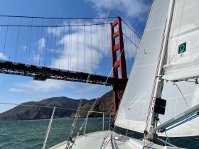 A stunning view of a sailboat navigating under the iconic Golden Gate Bridge, showcasing the beautiful scenery of San Francisco Bay.