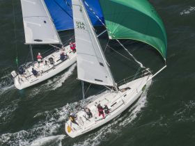 Two sailboats race through the waves, showcasing the thrill of competitive sailing — a perfect scene for sailing enthusiasts and adventure seekers.