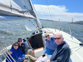 A cheerful group enjoys a sailing trip with the iconic Golden Gate Bridge in the background, capturing the essence of friendship and adventure on the water.
