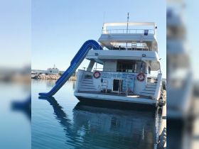 A stunning view of a yacht equipped with a water slide, docked in calm waters — perfect for family fun and aquatic adventures.