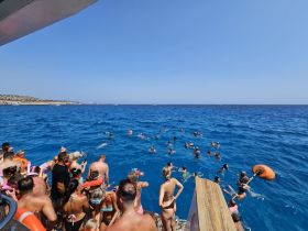 A lively group enjoys swimming in the vibrant blue waters, creating a perfect atmosphere for fun and relaxation during their boat trip.