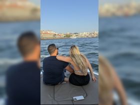 A couple enjoys a romantic moment on a boat, overlooking a beautiful waterfront cityscape — perfect for intimate getaways or sunset cruises.
