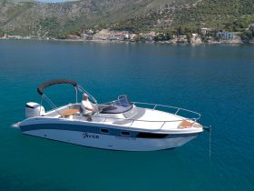 A sleek Saver boat glides through crystal-clear waters, showcasing its elegant design and perfect for leisurely outings along the coast.