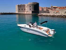 A sleek speedboat navigates the turquoise waters near a historic fort, showcasing the perfect blend of adventure and scenic beauty.