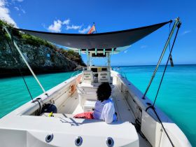 A serene view inside a boat, showcasing comfortable seating and a shaded helm area, perfect for relaxing while enjoying the turquoise waters.
