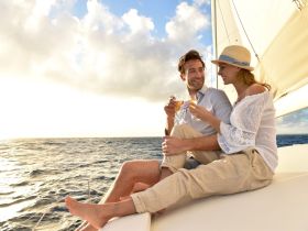 A couple enjoys cocktails while sailing at sunset, creating a romantic atmosphere perfect for special occasions on the water.