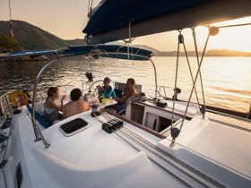 A group enjoys a sunset meal on a sailboat, creating a perfect atmosphere for relaxation and celebration on the water.