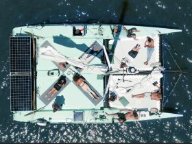 A group of friends relaxes on the deck of a catamaran, enjoying the sun and water — the perfect setting for a day of leisure on the sea.
