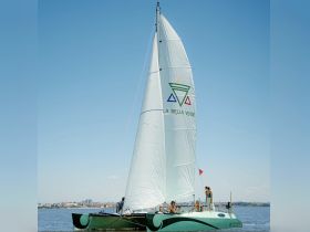 A lively group enjoys a sailing experience on a catamaran named 'La Bella Verde,' showcasing the joy of on-water activities under a clear blue sky.