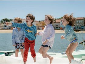 A joyful group of children enjoying their time on a boat, pointing and laughing, capturing the essence of fun-filled moments on the water.